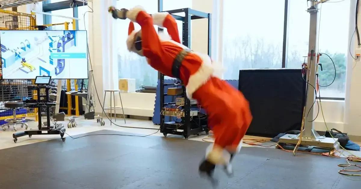 Robô Atlas da Boston Dynamics realizando um backflip com traje de Papai Noel